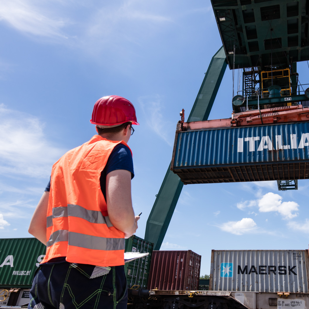 Foto eines Mitarbeiters der RheinCargo, der über einen Containertransport wacht